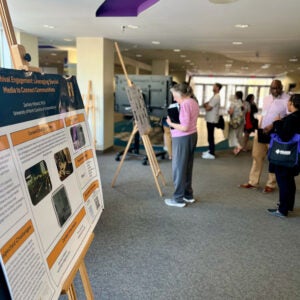 Groups of people look at posters displayed on the first floor of a library.